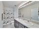 Bright bathroom featuring double sinks, a decorative shower curtain, and neutral tile flooring at 6929 Breezy Palm Dr, Riverview, FL 33578