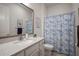 Bathroom featuring a large mirror, granite countertop, vanity, toilet, and shower with blue, leafy patterned curtain at 7432 Paradiso Dr, Apollo Beach, FL 33572