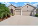 Attractive exterior elevation with a two-car garage, stone-accented entryway, mature landscaping, and concrete driveway at 7432 Paradiso Dr, Apollo Beach, FL 33572