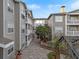 Courtyard of apartments featuring gray siding, white trim, a brick paver walkway, and mature landscaping at 800 S Dakota Ave # 205, Tampa, FL 33606