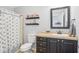 Well-lit bathroom with shower featuring blue seashell-themed shower curtain, sink with black cabinets, and tan countertops at 8448 Fantasia Park Way, Riverview, FL 33578