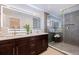 Modern bathroom featuring a double vanity, a large illuminated mirror, and a spacious glass-enclosed shower with stone floors at 10100 Paradise Blvd, Treasure Island, FL 33706