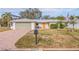 Well-kept home with a tidy front yard, brick driveway, a prominent mailbox, and an eye-catching orange front door at 10100 Paradise Blvd, Treasure Island, FL 33706