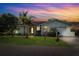 Charming single-story home featuring a well-manicured lawn and lush landscaping under a colorful evening sky at 1035 County Road 90, Palm Harbor, FL 34684