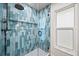 Modern shower with blue tile surround, glass door, rainfall shower head and window for natural light at 10562 99Th St, Largo, FL 33773