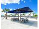 Outdoor seating area at the lagoon's beach featuring tables with umbrellas, palm trees, and blue skies at 10646 Pepper Dawn Cir, San Antonio, FL 33576