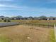 View of a large backyard with fence and pond, looking out at neighboring homes at 11333 June Briar Loop, San Antonio, FL 33576