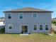 Backyard view of the two-story house, sliding glass door to patio, and an egg chair at 11333 June Briar Loop, San Antonio, FL 33576