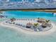 Aerial shot of an island retreat with tiki hut umbrellas and lounge chairs on the white sand beach by the lagoon at 11333 June Briar Loop, San Antonio, FL 33576