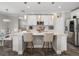 Modern kitchen island with white cabinets, stainless steel appliances, pendant lighting, and bar stool seating at 11333 June Briar Loop, San Antonio, FL 33576