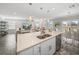 Wide view of the kitchen island and open layout, showing stainless steel appliances, white cabinets, and adjacent living spaces at 11333 June Briar Loop, San Antonio, FL 33576