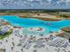 Aerial view of a community lagoon with white sand beach, lounge chairs, cabanas, and clear turquoise water at 11333 June Briar Loop, San Antonio, FL 33576