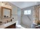 This bathroom features a walk-in shower, neutral tile and a vanity with a sink and custom framed mirror at 1211 Carolyn Ln, Clearwater, FL 33755