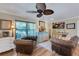 Cozy living room with hardwood floors, showcasing comfortable leather seating, a ceiling fan and a view to the yard at 1211 Carolyn Ln, Clearwater, FL 33755