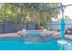 A beautiful screened-in pool featuring a spa with a small waterfall and lush green landscaping at 12478 93Rd Way, Largo, FL 33773