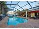 Backyard pool with a jacuzzi, brick patio, covered outdoor kitchen, tropical landscaping, and lounge chairs at 12478 93Rd Way, Largo, FL 33773