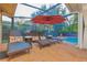 Screened patio featuring chaise lounges, a red umbrella, and a pool with a view of the backyard at 12478 93Rd Way, Largo, FL 33773