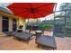 Screened patio featuring chaise lounges, a red umbrella, and access to the backyard at 12478 93Rd Way, Largo, FL 33773