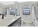 Stylish bathroom featuring double sinks, quartz countertops, tile shower, and a bright window at 12704 Vander Way, New Port Richey, FL 34654