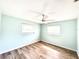 Bright bedroom featuring wood-look floors, two windows, and a ceiling fan at 13290 75Th Ave, Seminole, FL 33776