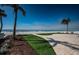 Landscaped backyard with palm trees, lush grass, and a view of the ocean and beach at 15912 Gulf Blvd, Redington Beach, FL 33708