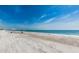 Inviting beach scene with an umbrella, chair, and calm ocean view under a partly cloudy sky at 15912 Gulf Blvd, Redington Beach, FL 33708