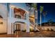 An illuminated front entryway with ornate ironwork, exterior staircase and elegant lighting at night at 15912 Gulf Blvd, Redington Beach, FL 33708