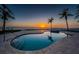 Beautiful swimming pool overlooking the beach at sunset surrounded by palm trees at 15912 Gulf Blvd, Redington Beach, FL 33708