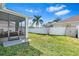 Green backyard featuring an enclosed patio, a lawn, privacy fencing, and some palm trees at 1645 Fennsbury Ct, Wesley Chapel, FL 33544