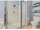 Bathroom showcasing a glass enclosed shower, gray tile, shelves, decor, and a toilet at 1645 Fennsbury Ct, Wesley Chapel, FL 33544