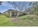 A beautiful backyard featuring lush green grass, mature trees, and a screened lanai at 237 Shell Falls Dr, Apollo Beach, FL 33572