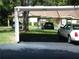 Carport in front of the house with grass area, a view of foliage, and dark pavement at 2567 Bentley Dr, Palm Harbor, FL 34684