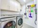 Bright laundry room featuring a washer, dryer, storage cabinets, and cleaning supplies at 2902 N Shoreview Pl, Tampa, FL 33602