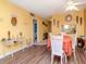 Open dining area with wood floors, yellow walls, adjacent to living area, and hallway leading to bedroom at 300 Glennes Ln # 208, Dunedin, FL 34698