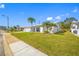 Front view of a white single-story home with palm trees and a well-manicured lawn at 4043 93Rd N Ter, Pinellas Park, FL 33782