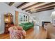 Cozy living room featuring hardwood floors, a fireplace, a green sofa, exposed wood beams, and large windows at 6010 17Th S Ave, Gulfport, FL 33707