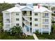 Exterior of condo building with multiple levels, white staircases, manicured landscaping and pastel color palette at 7611 34Th W Ave # 303, Bradenton, FL 34209