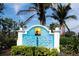 Entrance sign for 'Palma Sola Bay Club' framed by lush greenery and palm trees under a clear blue sky at 7611 34Th W Ave # 303, Bradenton, FL 34209