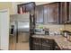 Cozy kitchen with stainless steel refrigerator, granite countertops, and dark wood cabinets at 780 Spring Flowers Trl, Brandon, FL 33511