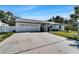 Wide driveway leading up to the house with a well-kept lawn, and mature landscaping at 9693 58Th N St, Pinellas Park, FL 33782