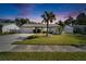 Exterior view of home with a front lawn, tall palm tree, and long driveway under a dusk sky at 9693 58Th N St, Pinellas Park, FL 33782