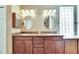 Bathroom featuring granite countertops, dual sinks, framed mirrors, decorative lighting, and a tiled shower at 1004 Regal Manor Way, Sun City Center, FL 33573