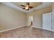 Bedroom with neutral walls, tiled floor, ceiling fan, and doorways to the bathroom and other rooms at 1004 Regal Manor Way, Sun City Center, FL 33573