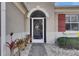 Close-up of a decorative front door with a brick path, shutters, and landscape at 1004 Regal Manor Way, Sun City Center, FL 33573