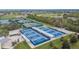 Aerial view of the community tennis courts showcasing pristine blue courts, sun shades, and lush landscaping at 1004 Regal Manor Way, Sun City Center, FL 33573