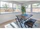 Bright dining area featuring a rustic wood table set, pale wood flooring, and large windows at 11005 Tyler Dr, Port Richey, FL 34668