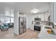 Bright and open kitchen with stainless steel appliances, white cabinets, and seamless transition to living room at 11005 Tyler Dr, Port Richey, FL 34668