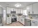 Modern kitchen featuring white cabinets, stainless steel appliances, quartz countertops, and stylish chevron backsplash at 11005 Tyler Dr, Port Richey, FL 34668