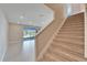 Carpeted staircase ascends towards a naturally lit living area with expansive windows and tiled flooring at 16725 Barnwood Pl, Bradenton, FL 34211