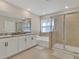 Bright bathroom featuring double vanities, a soaking tub, and a glass-enclosed shower at 16733 Glacier Bay Loop, Wimauma, FL 33598